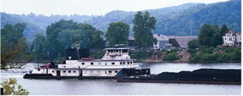 Picture of tow boat pushing a barge up the Ohio River past downtown Wheeling.